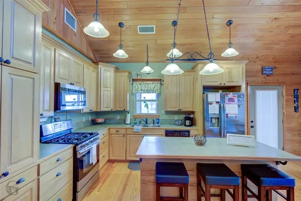 a kitchen with stainless steel appliances granite countertop a sink a stove and a wooden cabinets