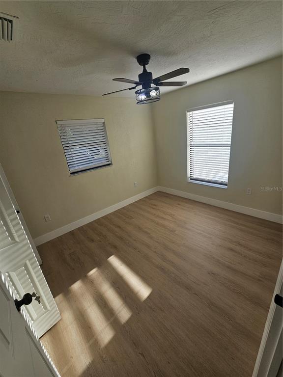 567 School Street Bronson, FL 32621 - Photo 14 of 23 an empty room with wooden floor chandelier fan and windows