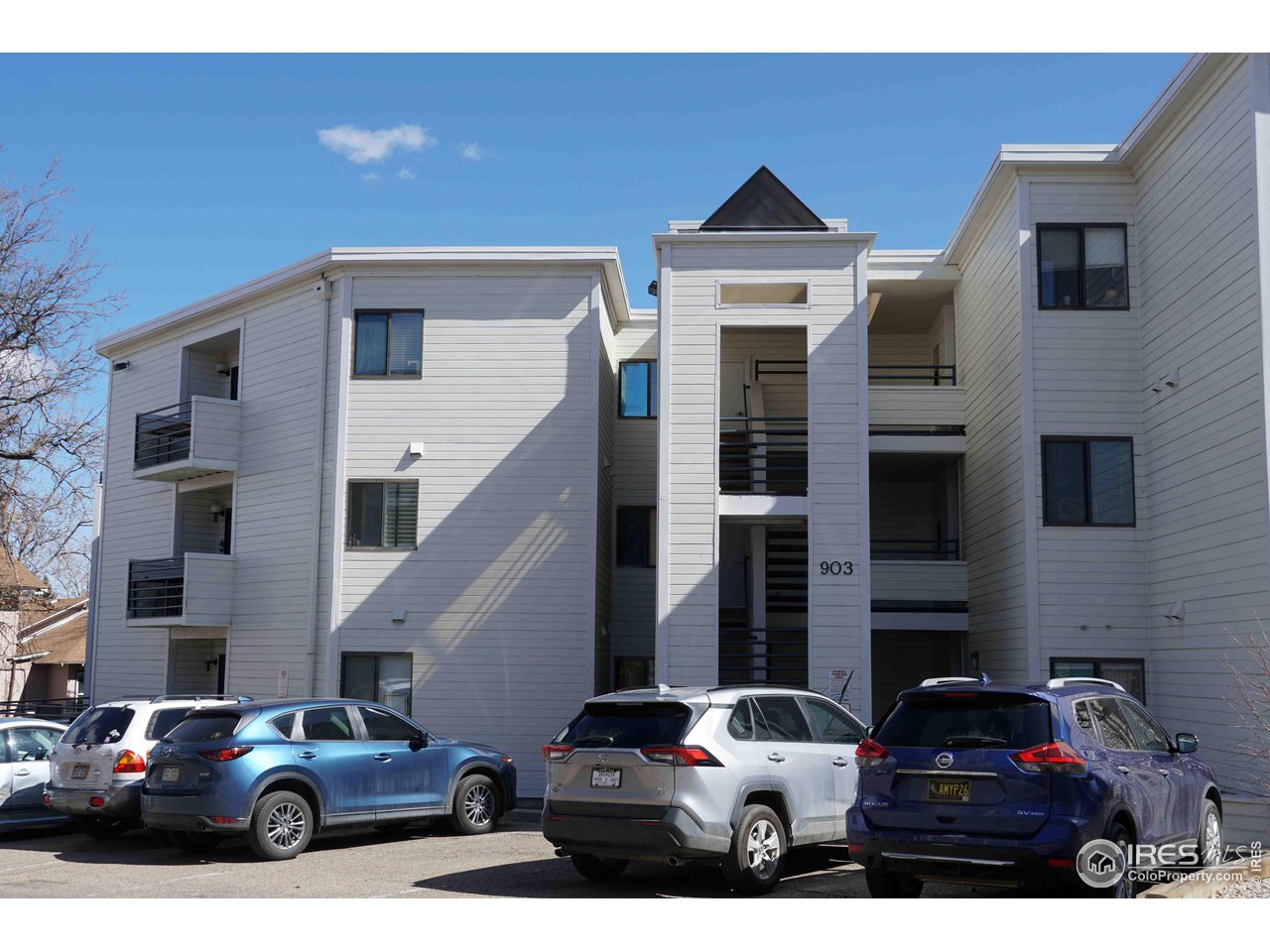 a front view of a building with cars parked