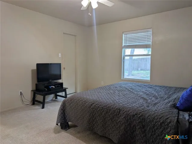 a bedroom with a bed and a flat tv screen on dresser