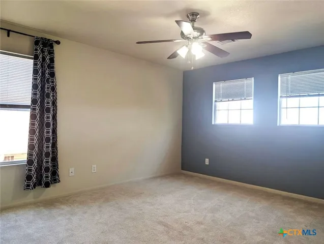 an empty room with windows and fan