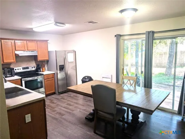 a kitchen with a table chairs refrigerator and microwave