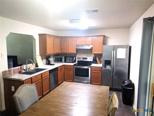 a kitchen with a refrigerator sink and wooden floor