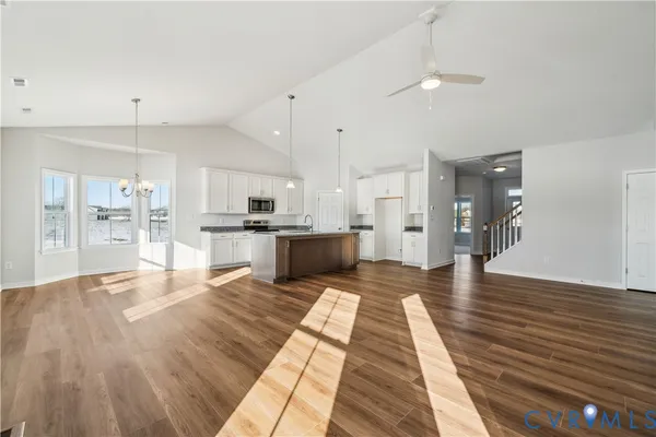 a large kitchen with stainless steel appliances kitchen island a large counter top and a chandelier