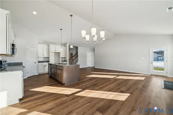 a view of a kitchen with kitchen island stainless steel appliances wooden floor and living room view