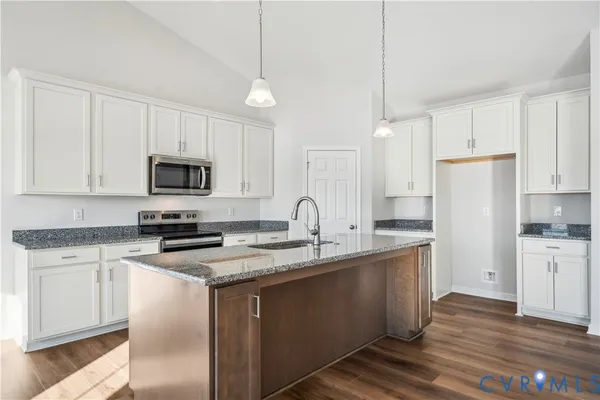 a kitchen with stainless steel appliances granite countertop a stove a sink dishwasher a refrigerator and white cabinets with wooden floor