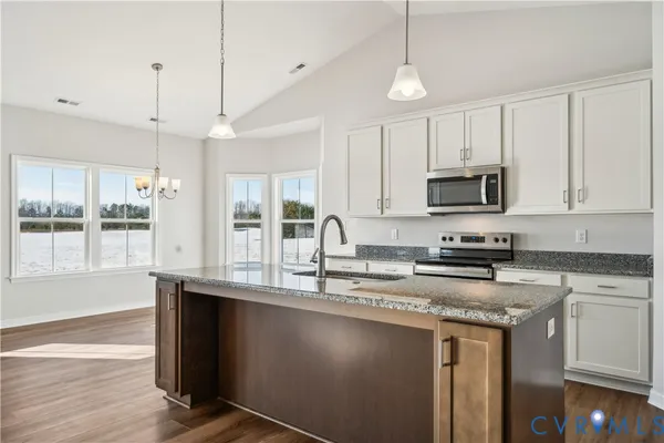 a kitchen with stainless steel appliances granite countertop a sink a stove a microwave a center island and cabinets