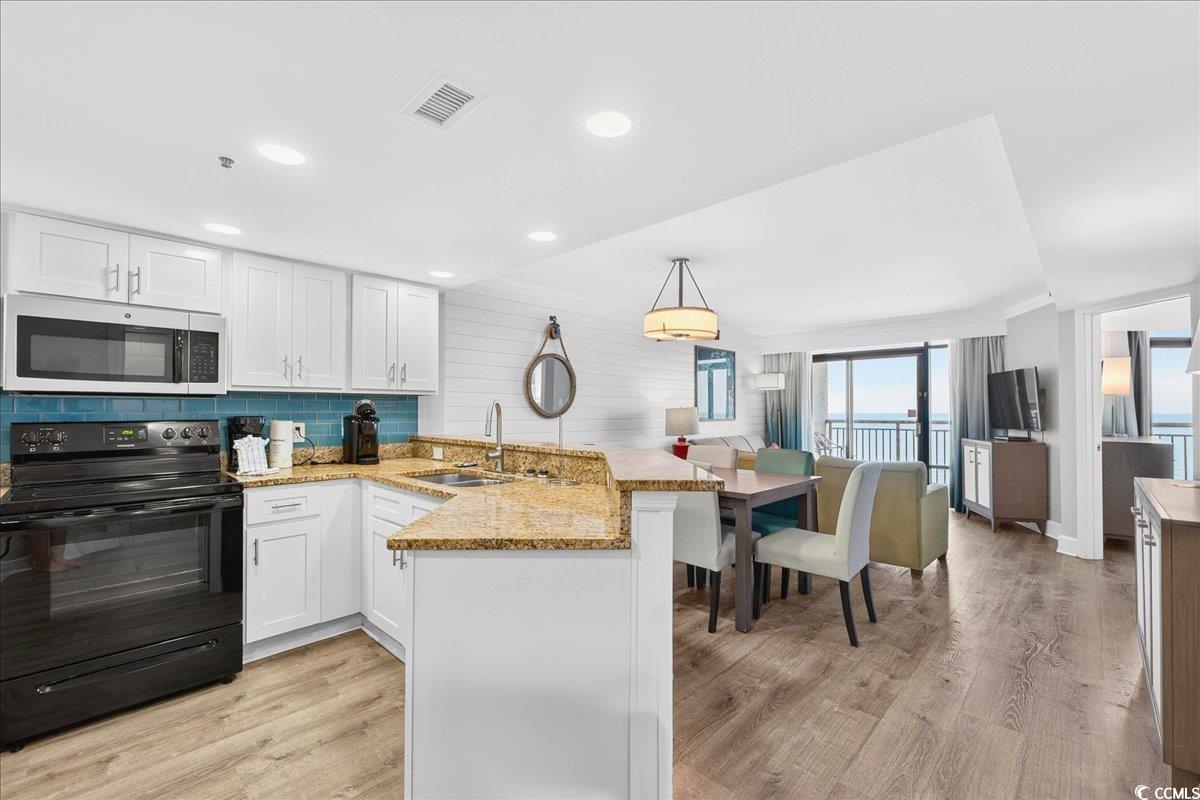 7200 North Ocean Boulevard, Unit 1155 Myrtle Beach, SC 29572 - Photo 26 of 40 Kitchen featuring a peninsula, black range with electric cooktop, light wood-type flooring, light stone counters, and white cabinets