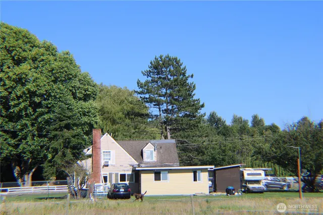 a view of a house with a small yard and a large tree
