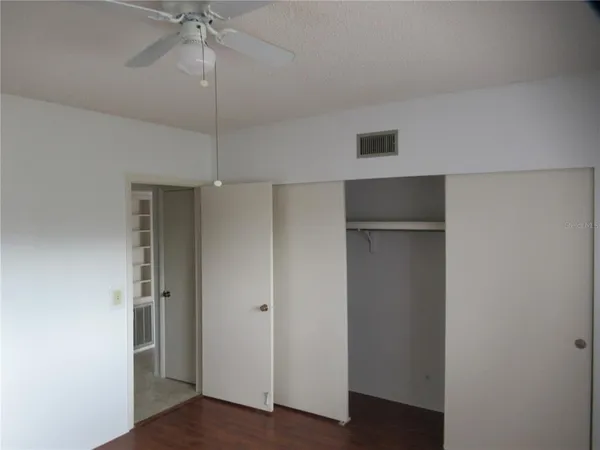 an empty room with wooden floor & closet area