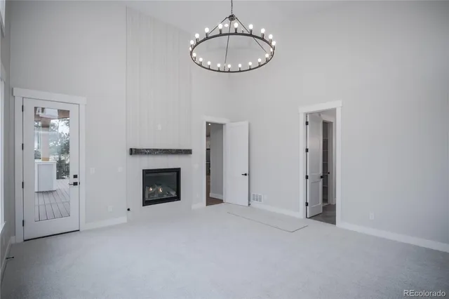 an empty room with chandelier fan and a fireplace