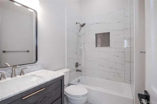 a bathroom with a granite countertop sink a toilet and shower