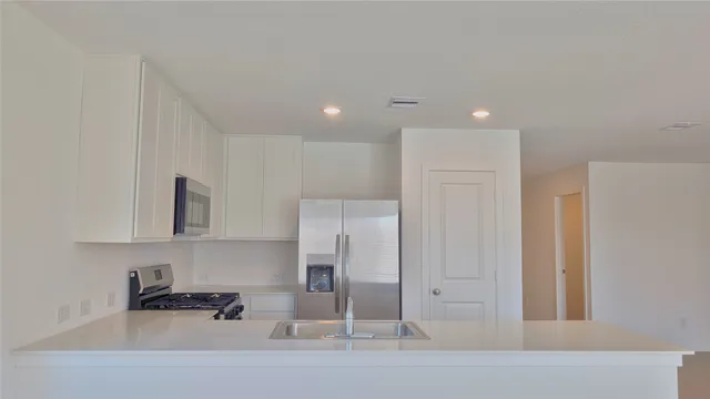a kitchen with stainless steel appliances granite countertop white cabinets and refrigerator