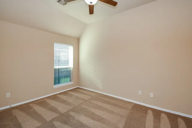 an empty room with chandelier fan and windows