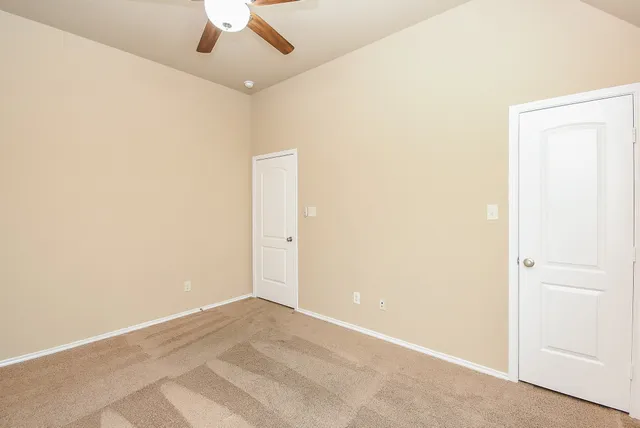 an empty room with a ceiling fan and carpet