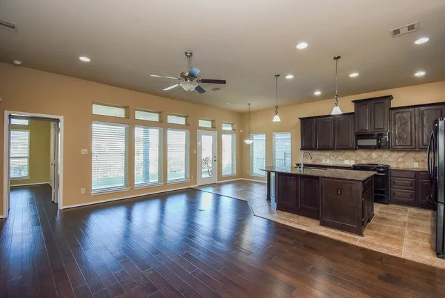 a large kitchen with stainless steel appliances granite countertop a stove and a wooden floors