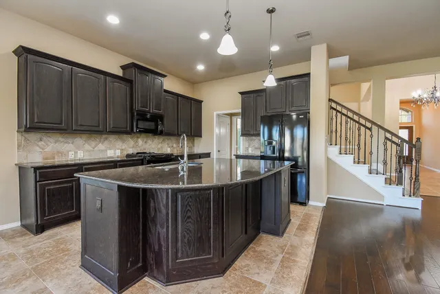 a kitchen with stainless steel appliances granite countertop a sink a stove and a refrigerator