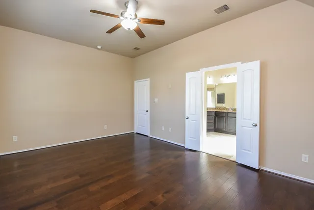 a view of a big room with wooden floor a chandelier fan and windows