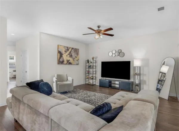 a living room with furniture a ceiling fan and a flat screen tv