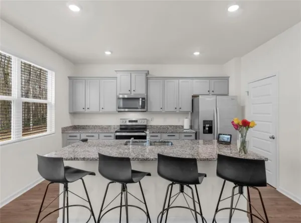 a kitchen with stainless steel appliances granite countertop a stove a refrigerator a sink a dining table and chairs