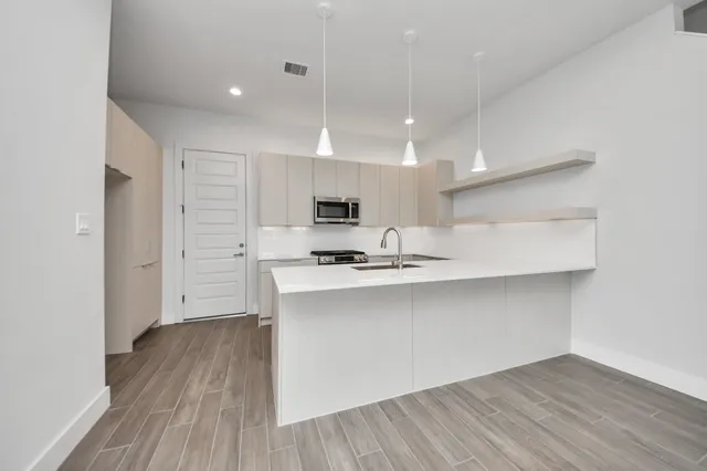 a kitchen with stainless steel appliances a sink cabinets and wooden floor