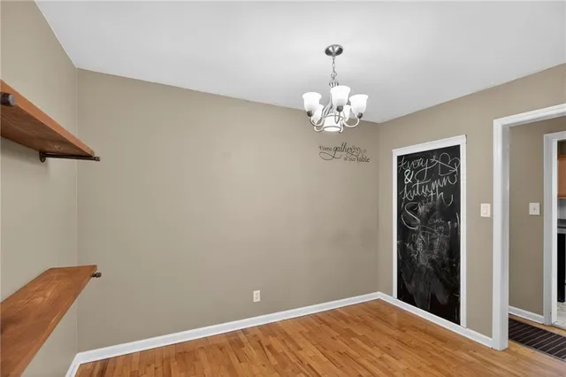a view of a hallway with wooden floor and chandelier