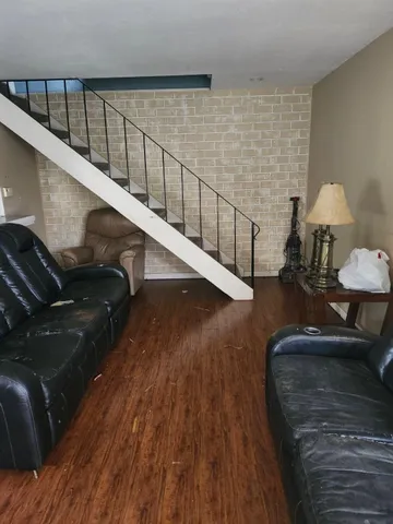 a living room with couches and a dining table with wooden floor