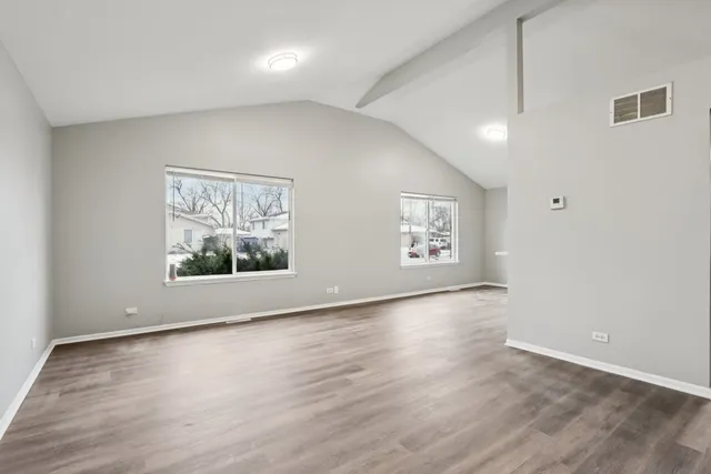 an empty room with wooden floor and window