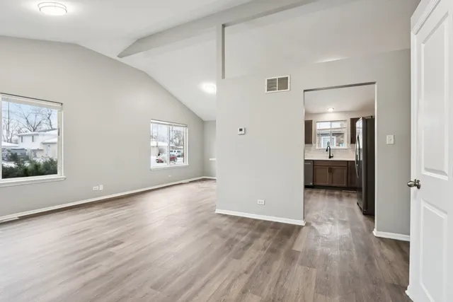 an empty room with wooden floor and windows