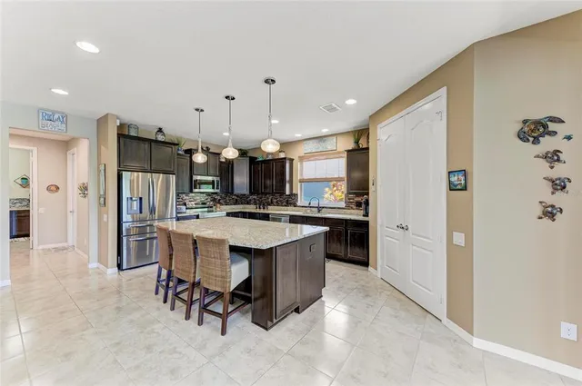 a large kitchen with stainless steel appliances granite countertop a stove a refrigerator and a large countertops with wooden floor