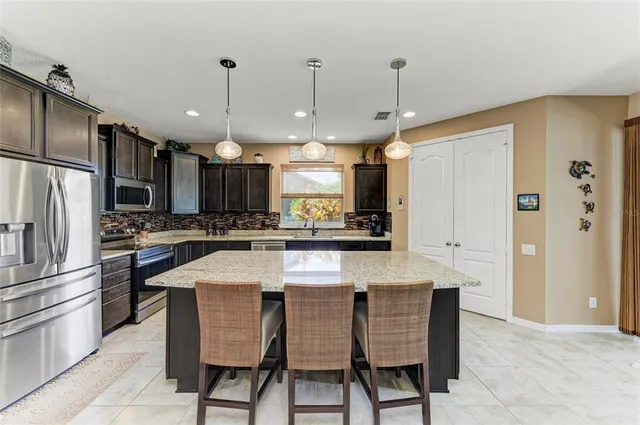 a kitchen with stainless steel appliances granite countertop a sink a stove and a refrigerator