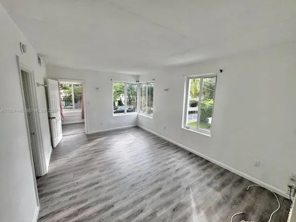 an empty room with windows entrance and wooden floor