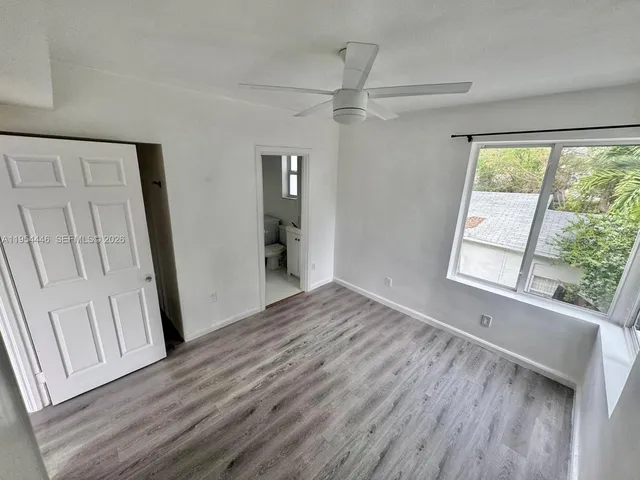 a view of empty room with wooden floor and fan