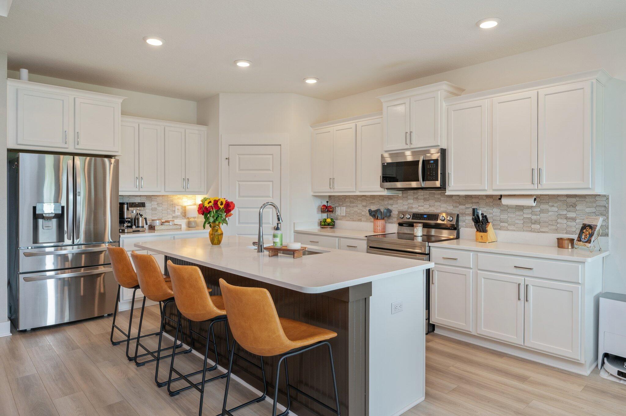 134 Blooming Cove Crestview, FL 32539 - Photo 10 of 50 a kitchen with stainless steel appliances a stove a sink a refrigerator and white cabinets with wooden floor