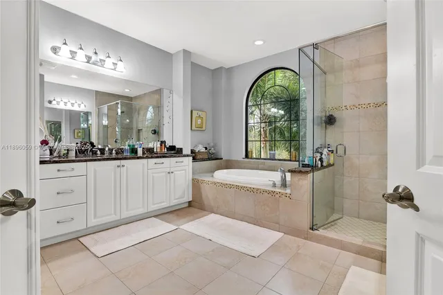 a spacious bathroom with a granite countertop tub a mirror a double vanity and a shower