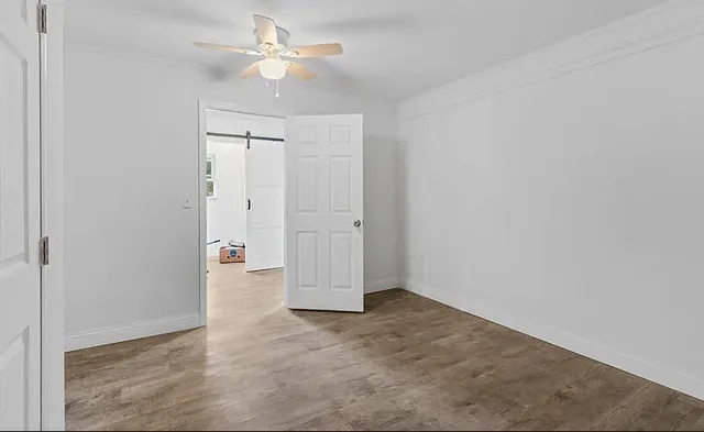 an empty room with closet and a ceiling fan