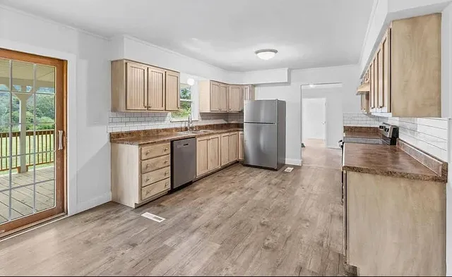 a kitchen with stainless steel appliances granite countertop a stove a sink and a refrigerator