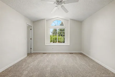 an empty room with a window and a chandelier fan