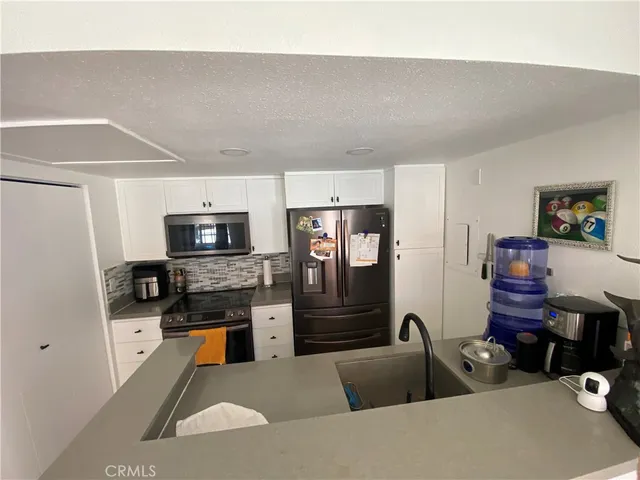 a living room with stainless steel appliances furniture a refrigerator a kitchen sink and a stove