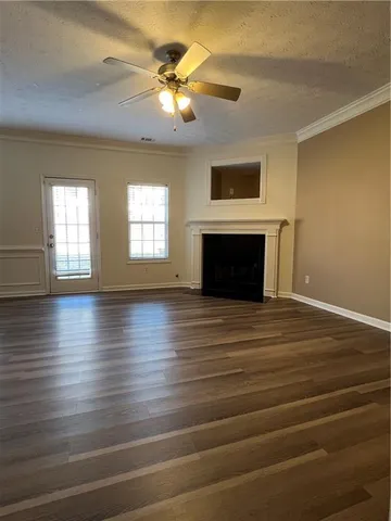 an empty room with wooden floor fireplace and windows