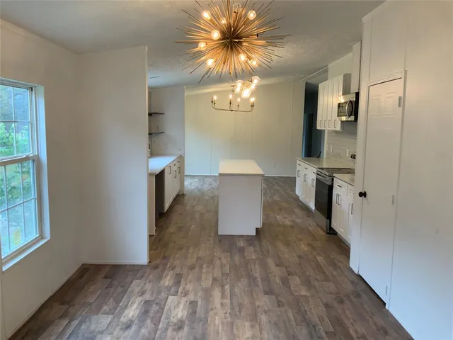 a view of a hallway with wooden floor and a chandelier