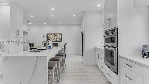 a kitchen with white cabinets and chairs