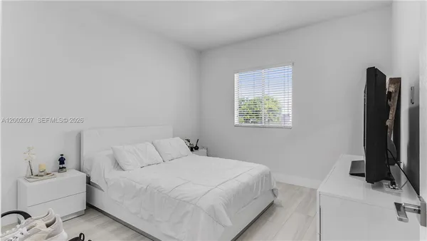 a bedroom with a bed and a potted plant on the dresser