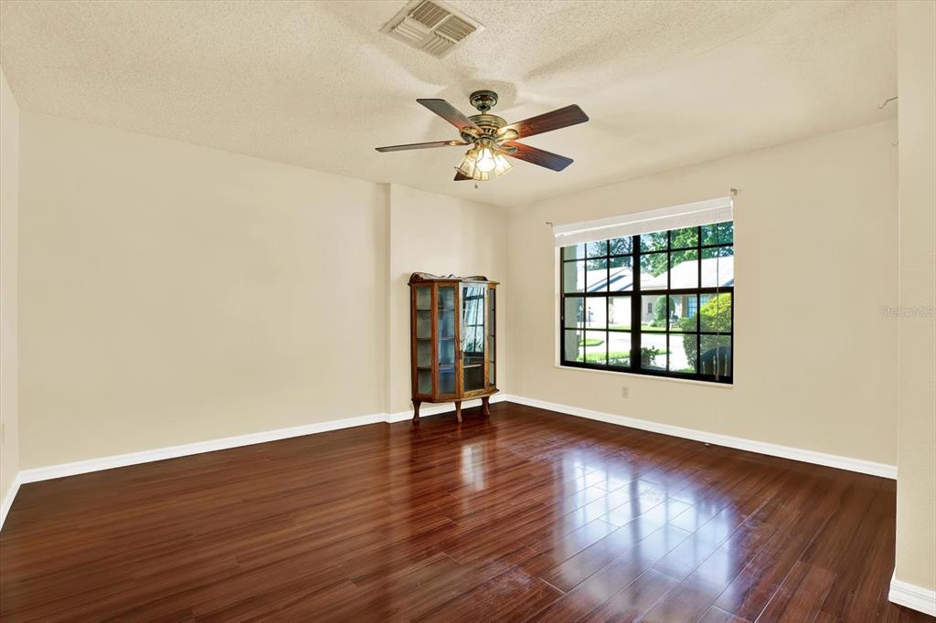 6654 Brambleleaf Drive Spring Hill, FL 34606 - Photo 6 of 27 an empty room with wooden floor chandelier fan and windows