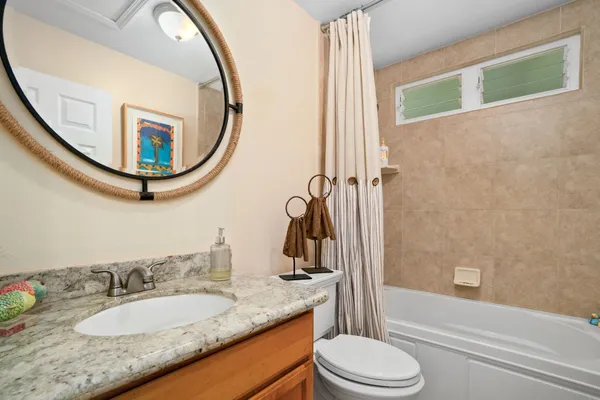 a bathroom with a granite countertop sink mirror vanity and toilet