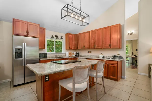 a kitchen with stainless steel appliances granite countertop a sink a stove a refrigerator and chairs