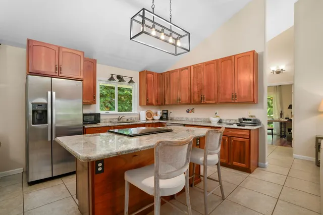 a kitchen with stainless steel appliances granite countertop a refrigerator a sink a stove and white cabinets with wooden floors