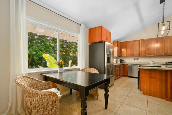 a kitchen with stainless steel appliances granite countertop a refrigerator a sink a stove and white cabinets with wooden floors