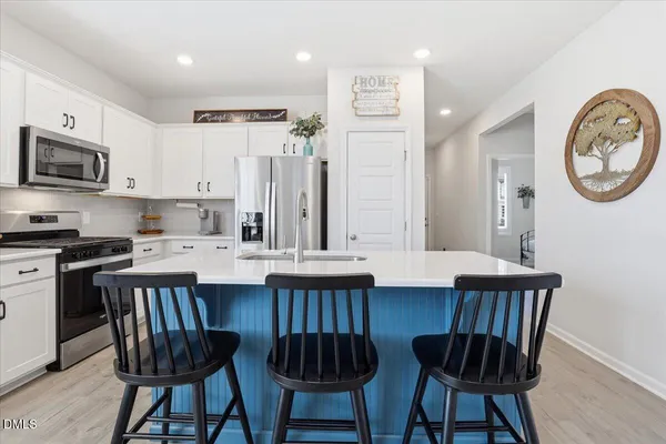 a kitchen with stainless steel appliances a microwave a stove a refrigerator and a dining table with wooden floor