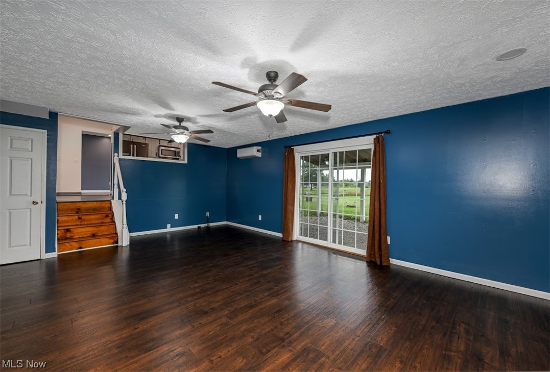 3368 Erhart Road Litchfield, OH 44253 - Photo 12 of 35 Empty room with a wall unit AC, a textured ceiling, dark hardwood floors, and ceiling fan